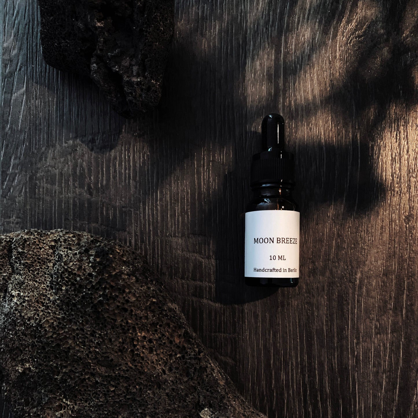 Bottle of Moun Berek skincare serum on a dark textured background